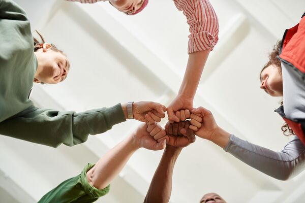 Grupo de personas juntando los puños en un gesto de colaboración.