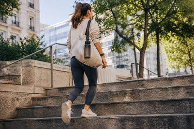 Mujer con ropa deportiva subiendo unas escaleras al aire libre.