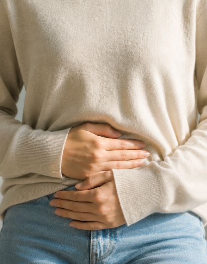 Mujer sentada con ambas manos apoyadas sobre el abdomen.