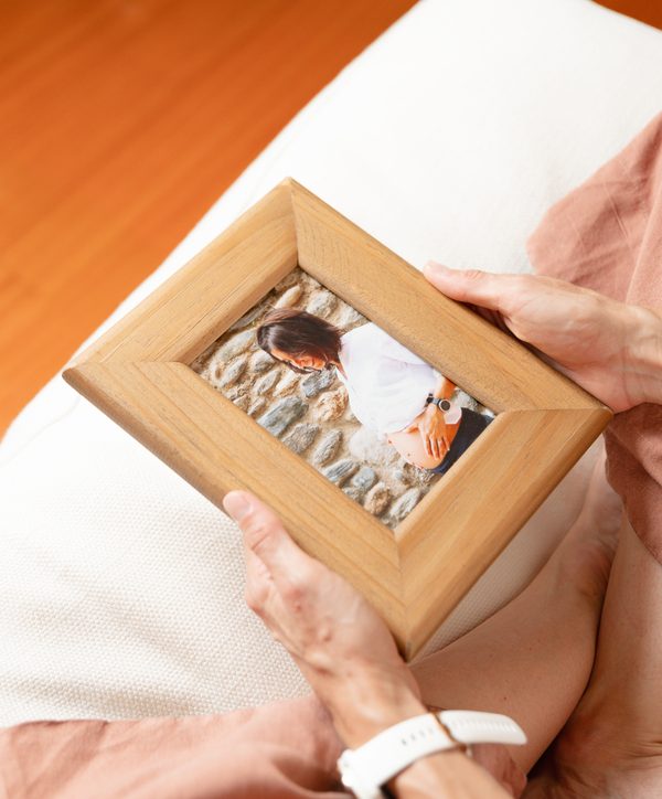Manos sosteniendo un marco con una fotografía de una mujer embarazada.